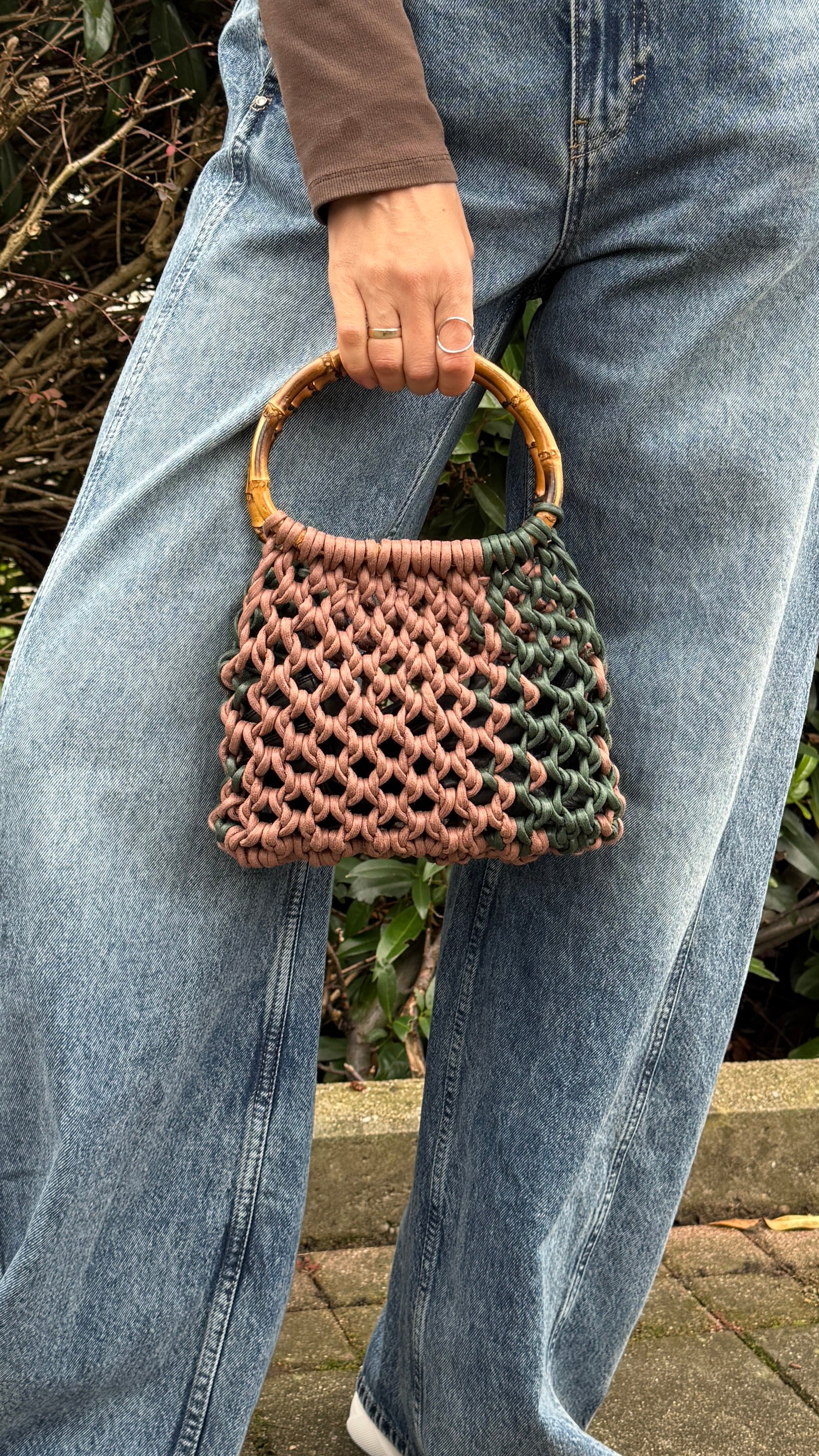 Person holding a woven handbag with a natural and brown color scheme.