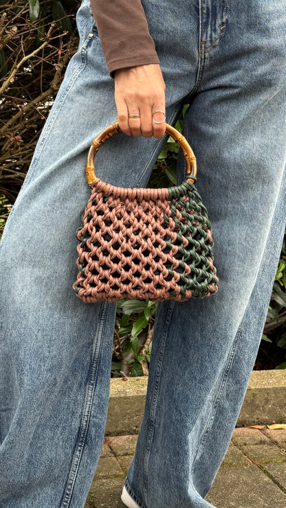 Person holding a woven handbag with a natural and brown color scheme.