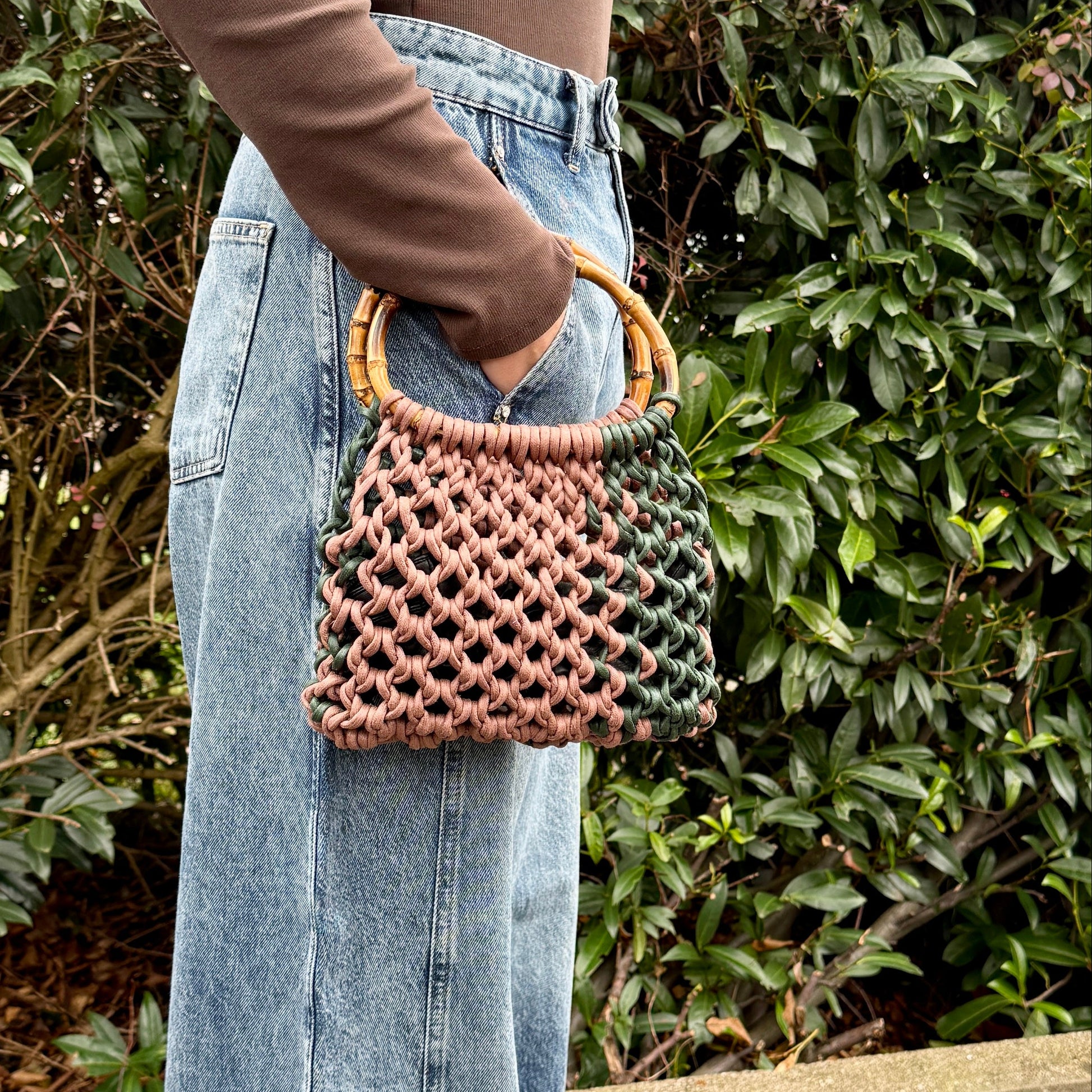 Person holding a woven macrame handbag with a blurred background
