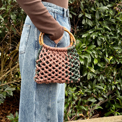 Person holding a woven macrame handbag with a blurred background
