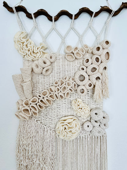 Decorative wall hanging with macrame design and coral reef details on a white background