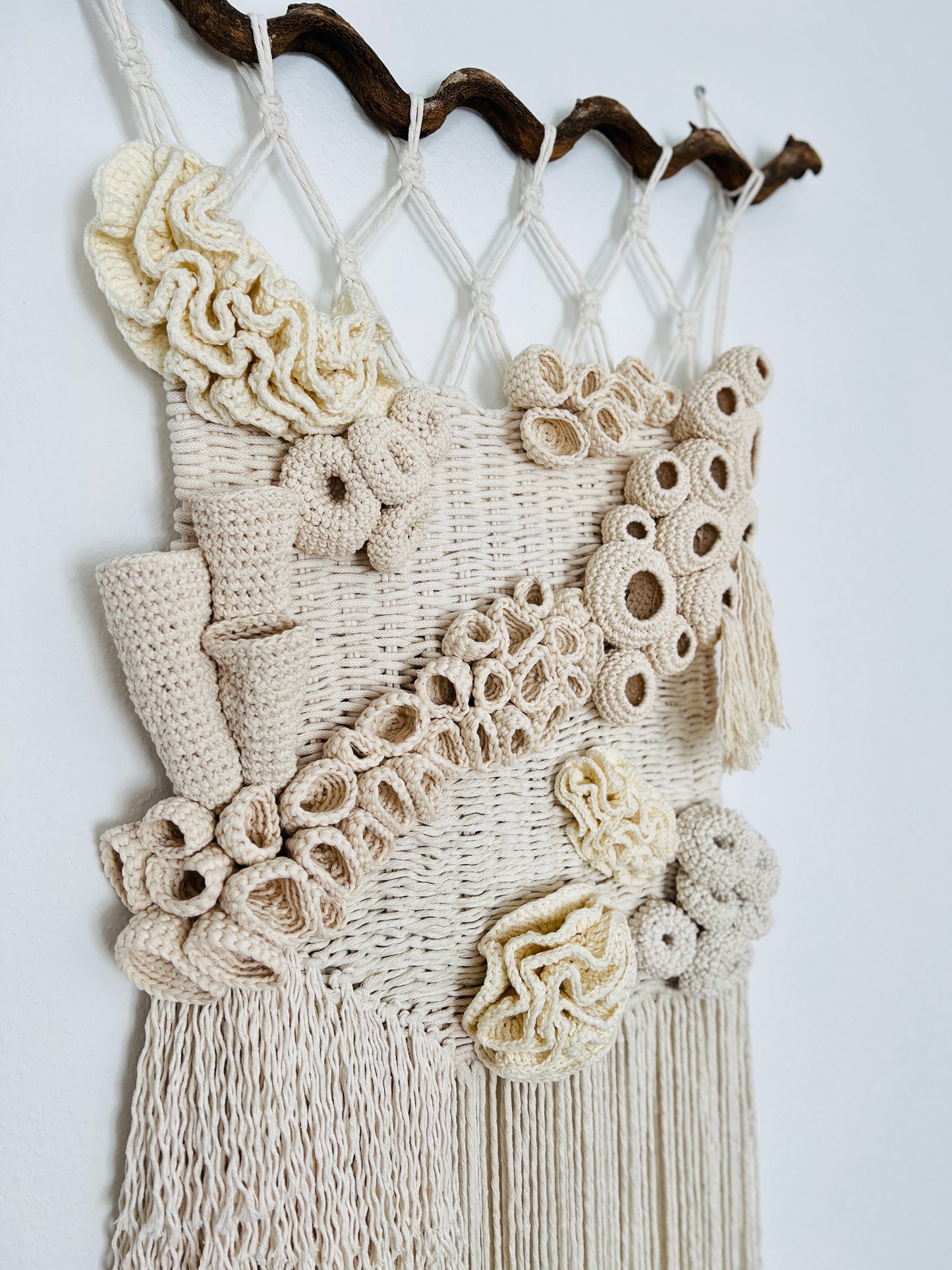 Macrame wall hanging with crochet details on a white background