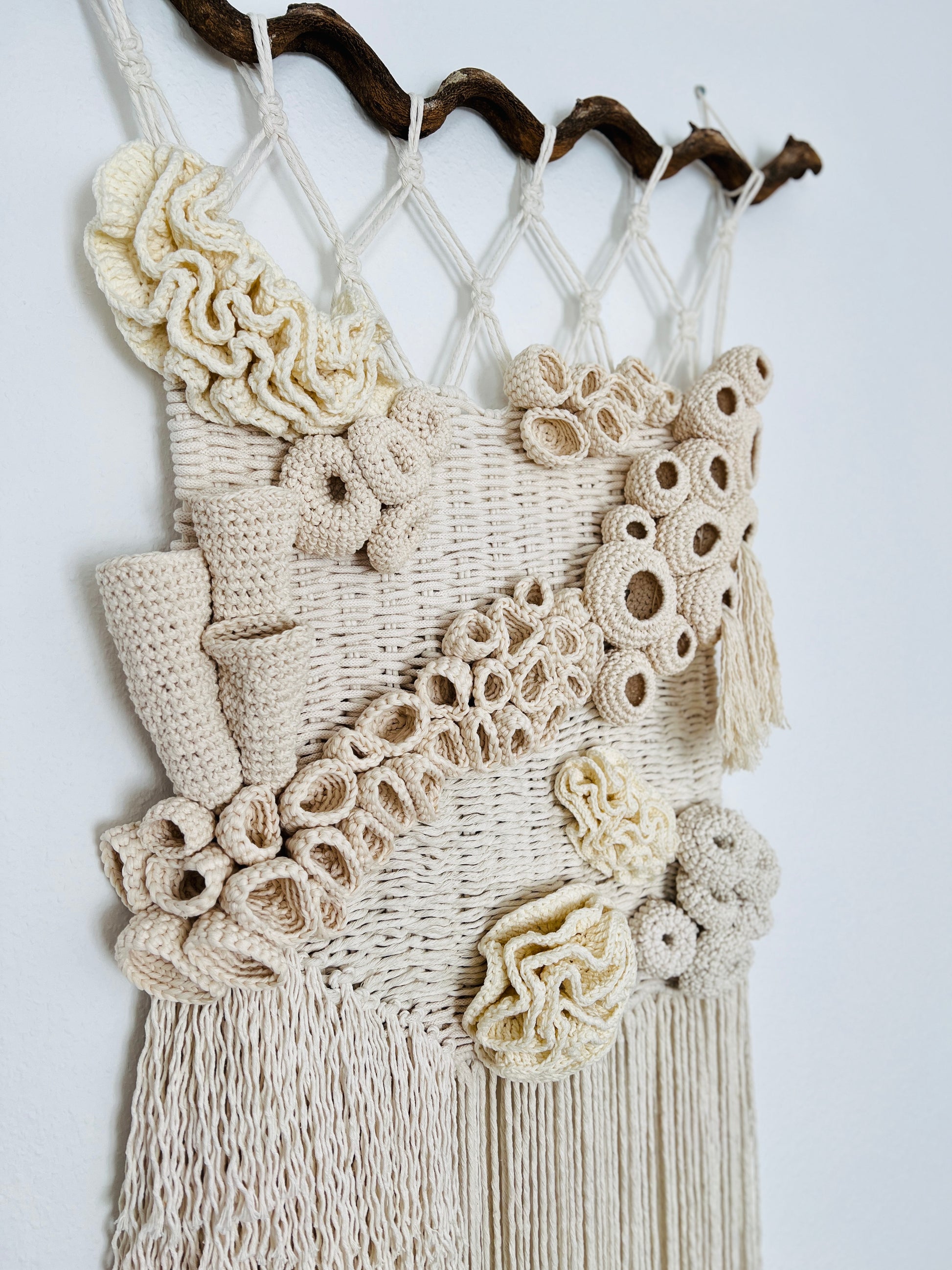 Macrame wall hanging with crochet details on a white background