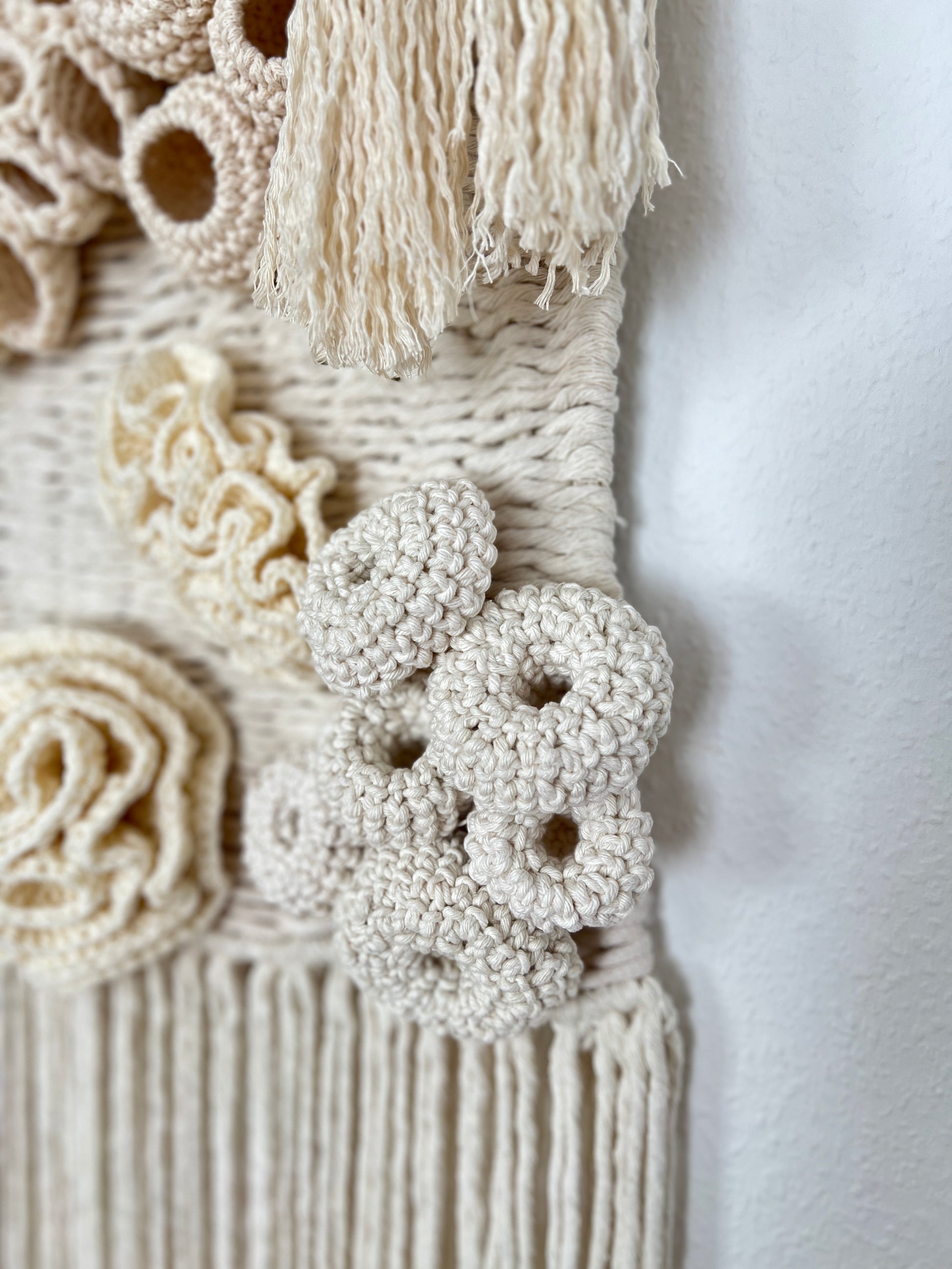 Close-up of a textured wall hanging with coral reef patterns and tassels.