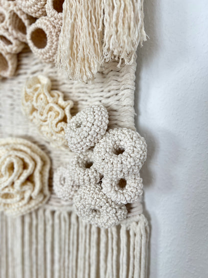 Close-up of a textured wall hanging with coral reef patterns and tassels.