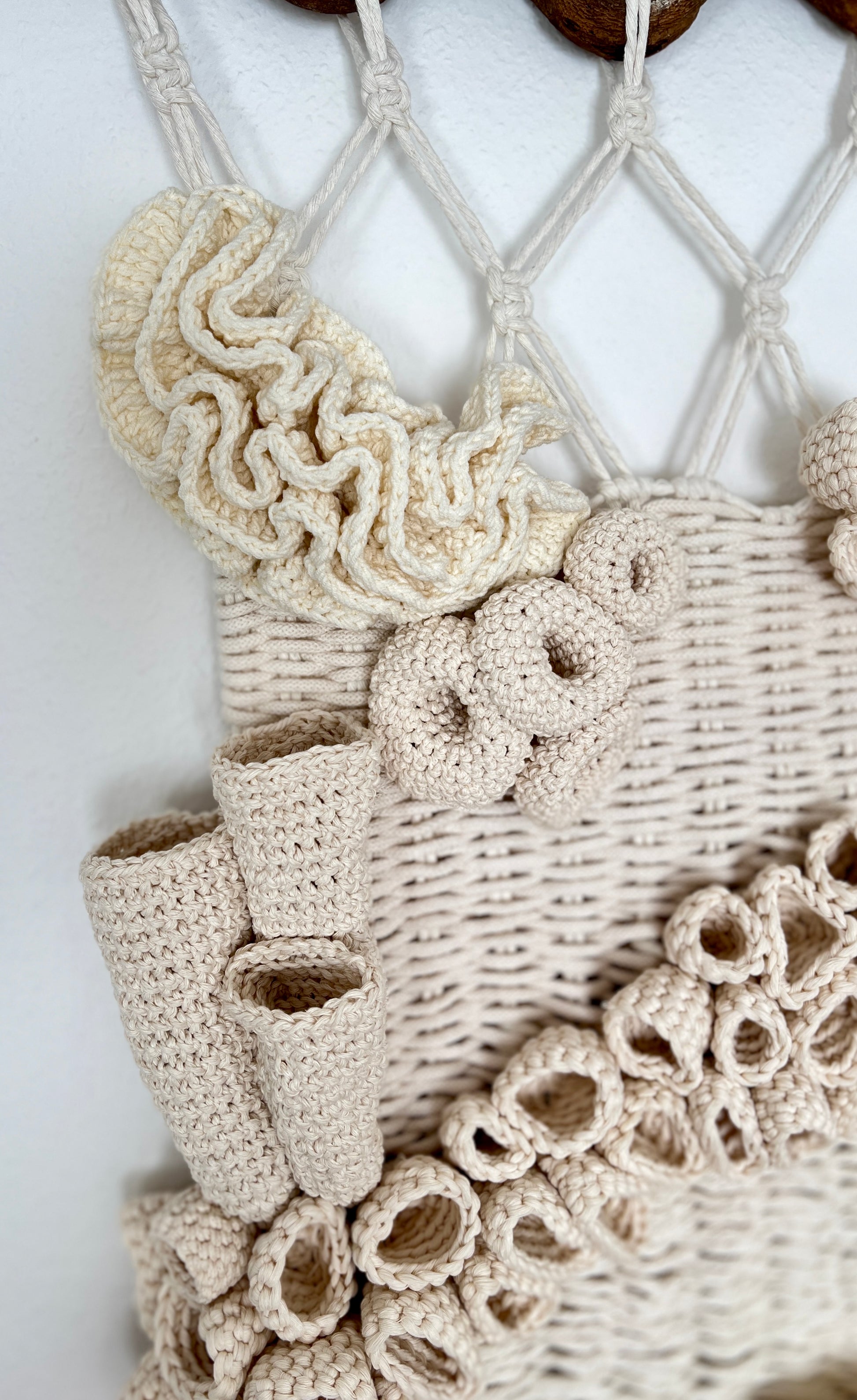 Close-up of a beige macrame wall hanging with crochet details