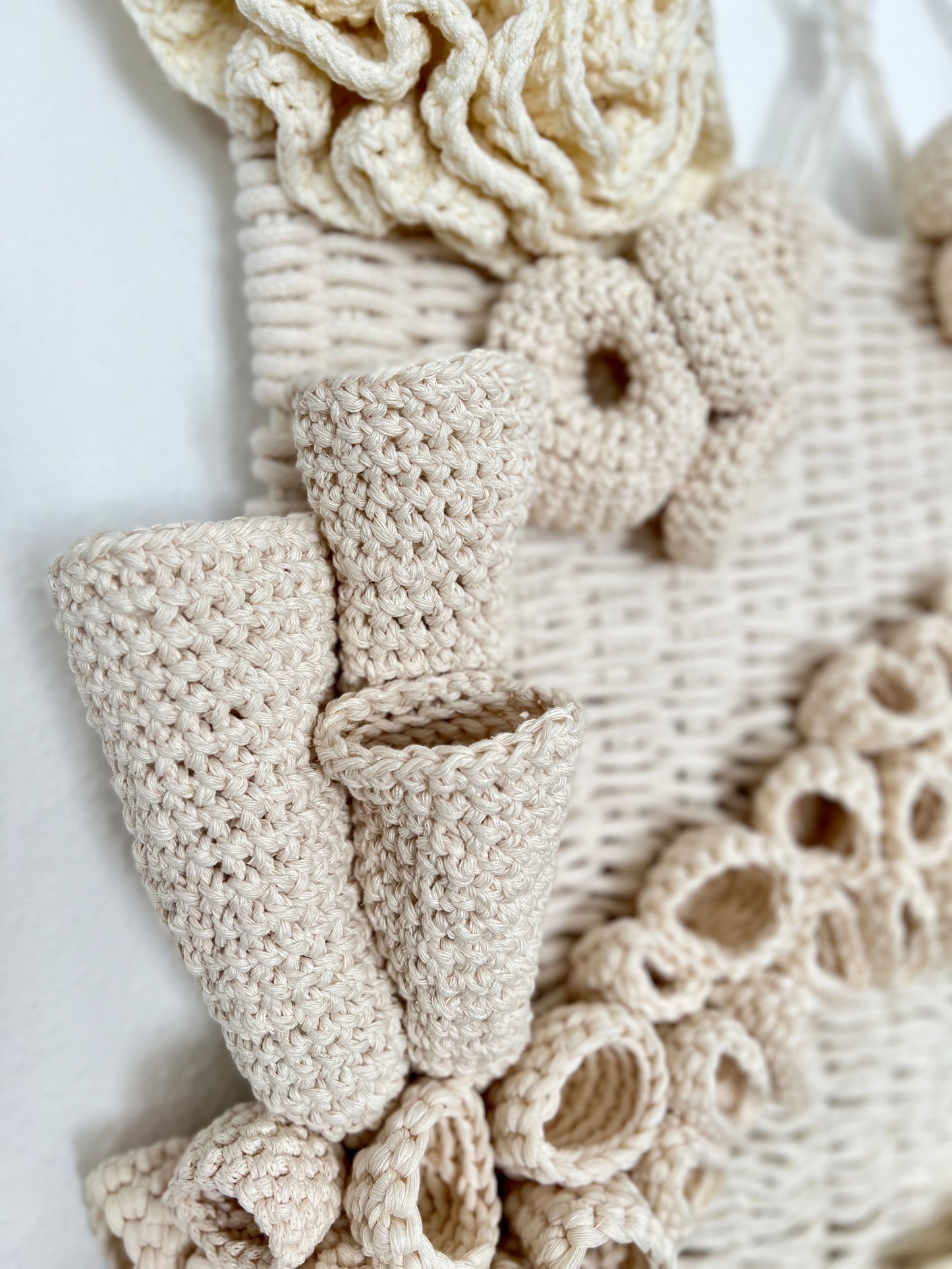 Close-up of textured beige fabric with various crochet details on a white background