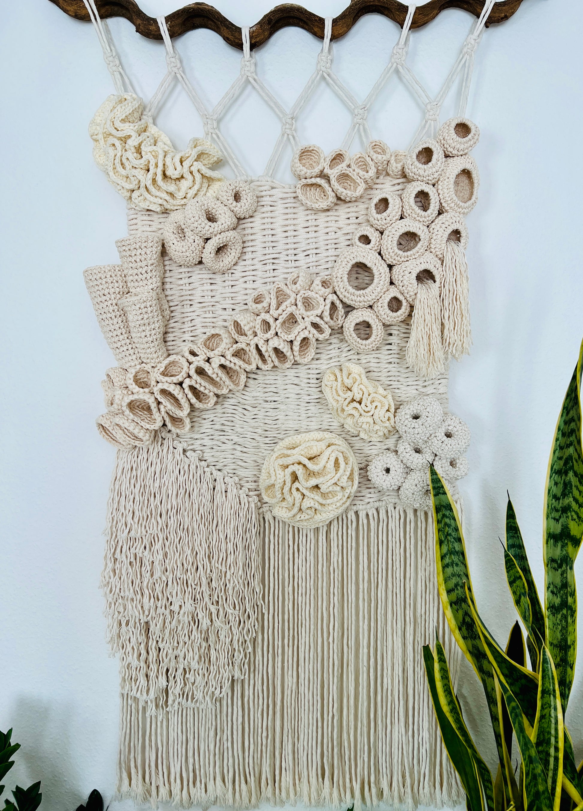 Macrame wall hanging with decorative accents and tassels on a light blue background