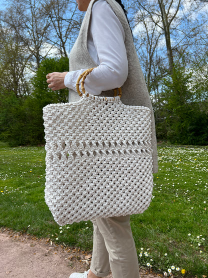Person wearing a textured beige sweater in an outdoor with macrame tote bag