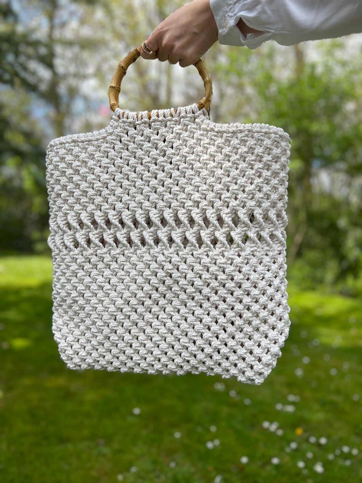 Hand holding a woven bag with a blurred natural background