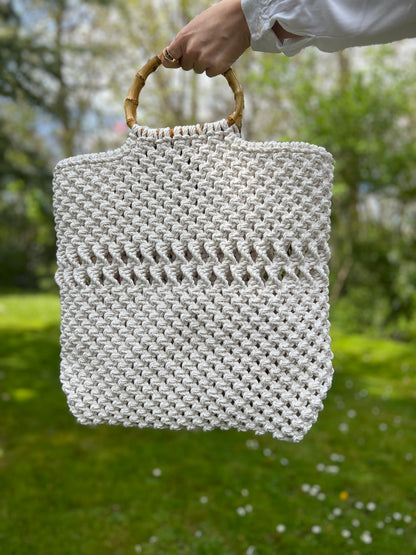 Hand holding a woven bag with a blurred natural background
