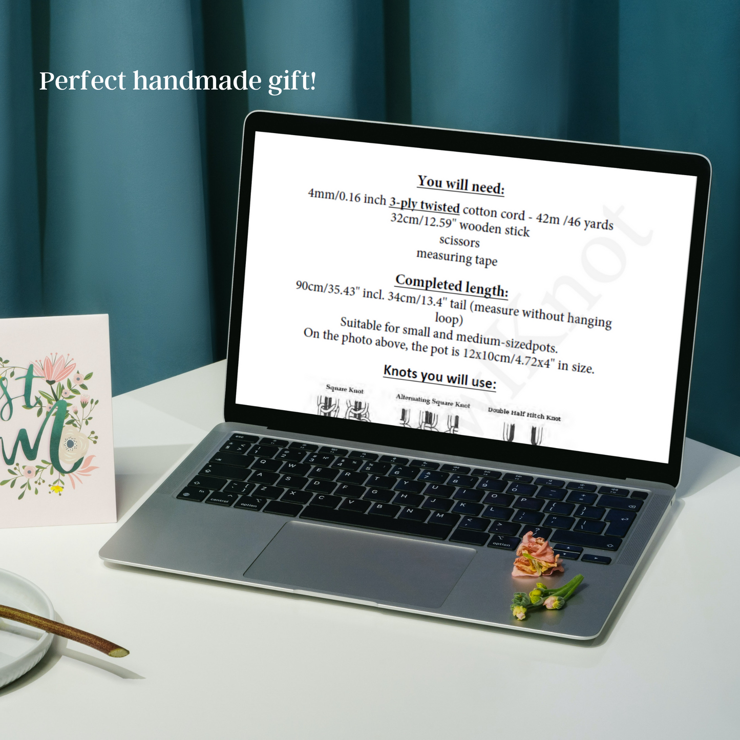 Laptop displaying a tutorial on a white surface with a card and small plant.