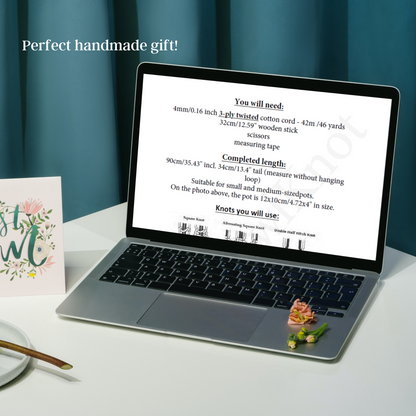 Laptop displaying a tutorial on a white surface with a card and small plant.