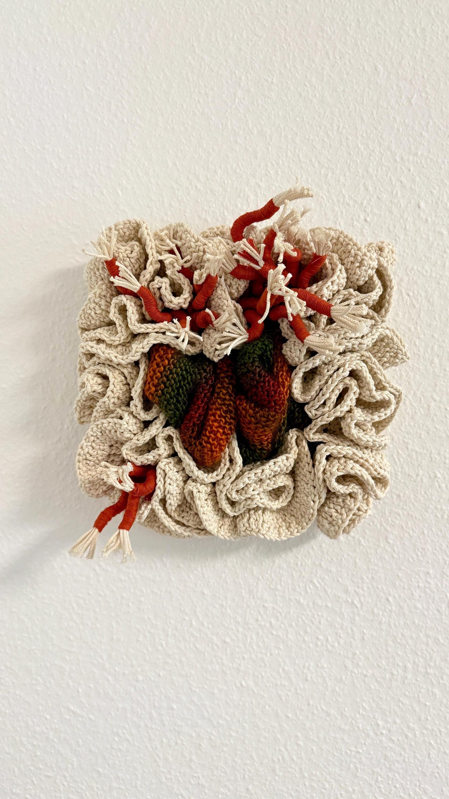 Decorative wall art with red and green elements on a textured beige background