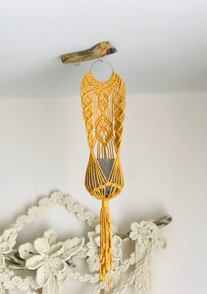 Yellow macrame wall hanging on a white wall with decorative elements.