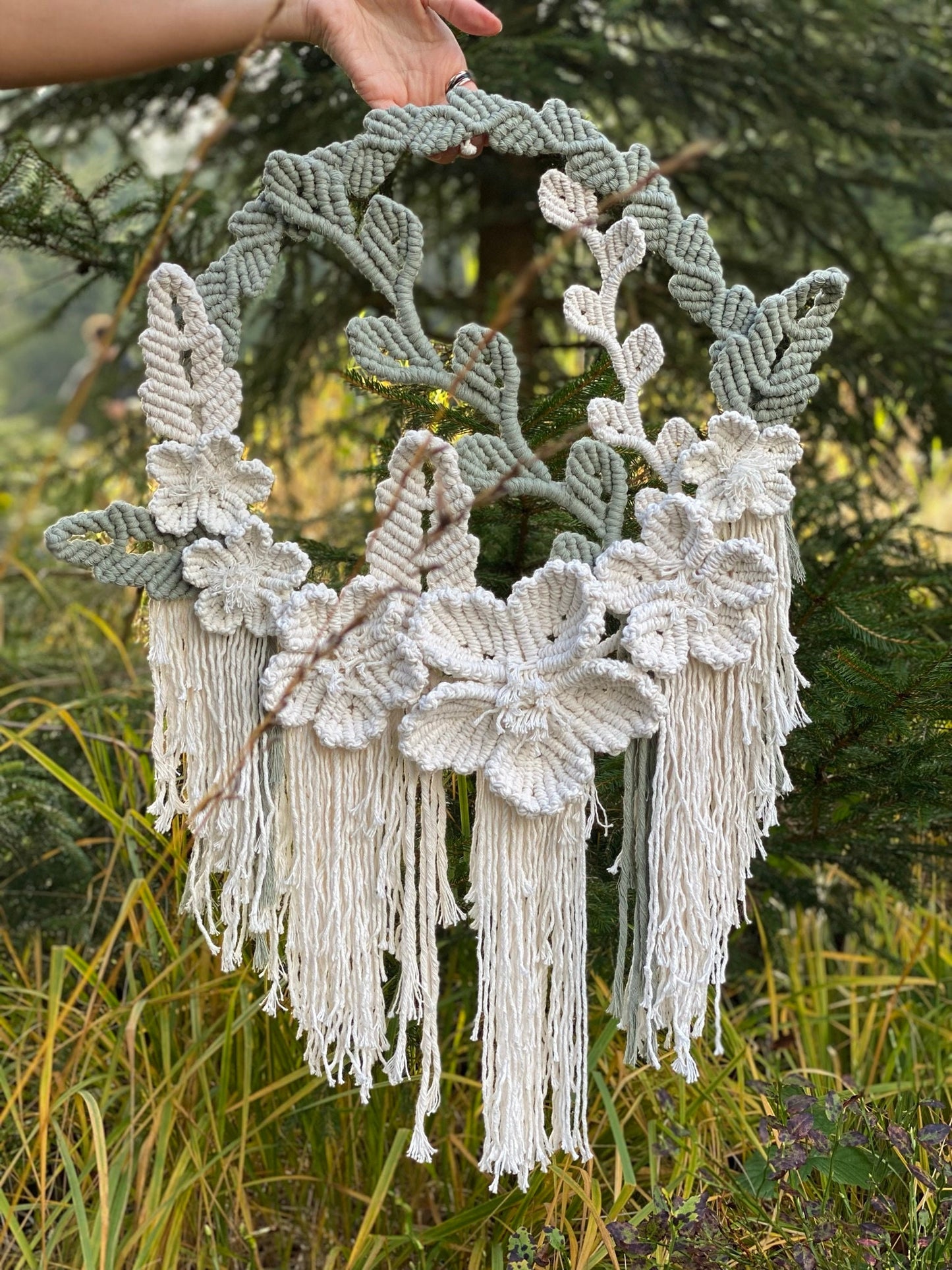 Macrame wall hanging with leaf patterns and tassels against a natural background