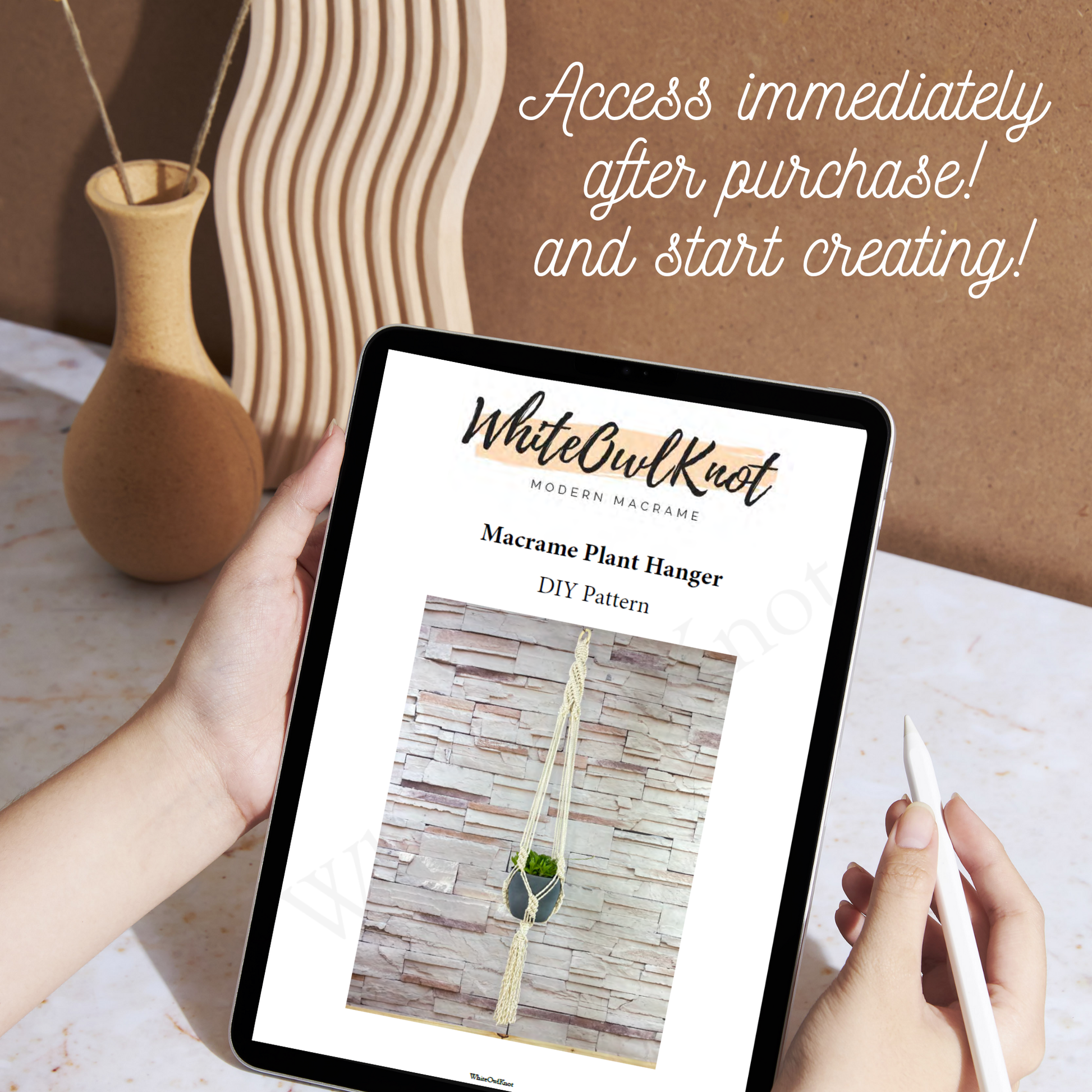 Person holding a tablet displaying a WhiteOwlKnot macrame plant hanger DIY pattern with decorative items in the background.