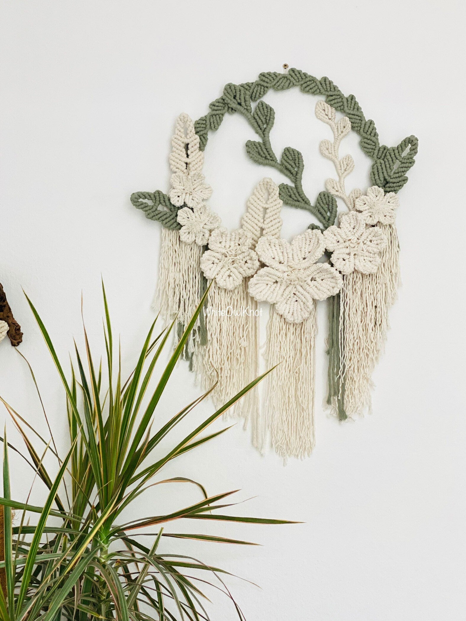 Decorative wall hanging with floral patterns and tassels on a white background