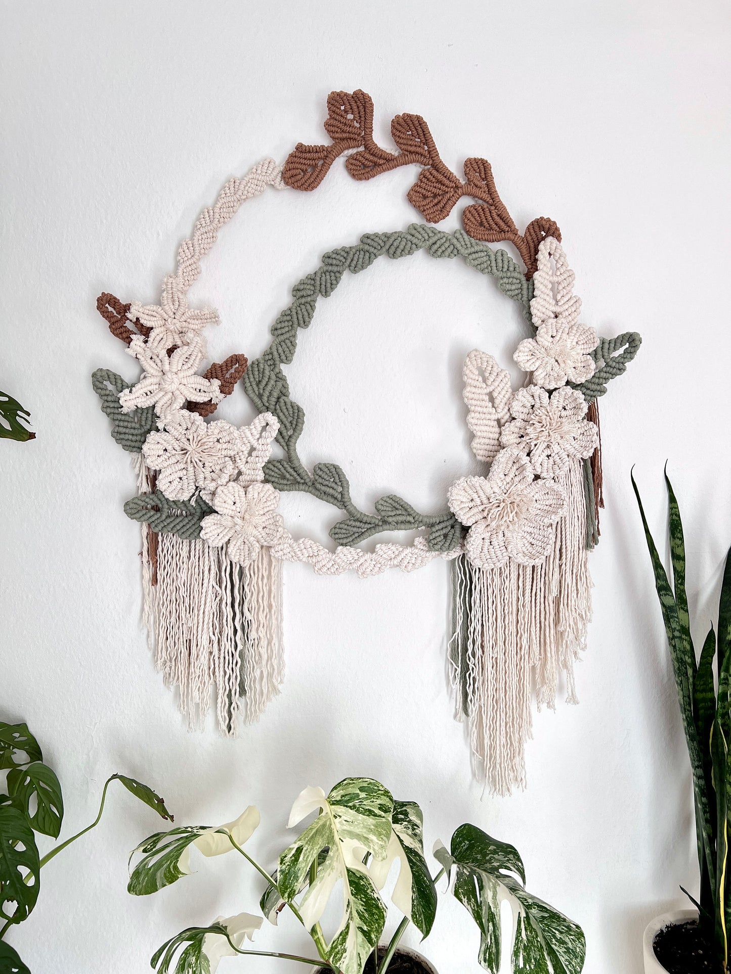 Decorative wall hanging with floral elements and tassels on a white background