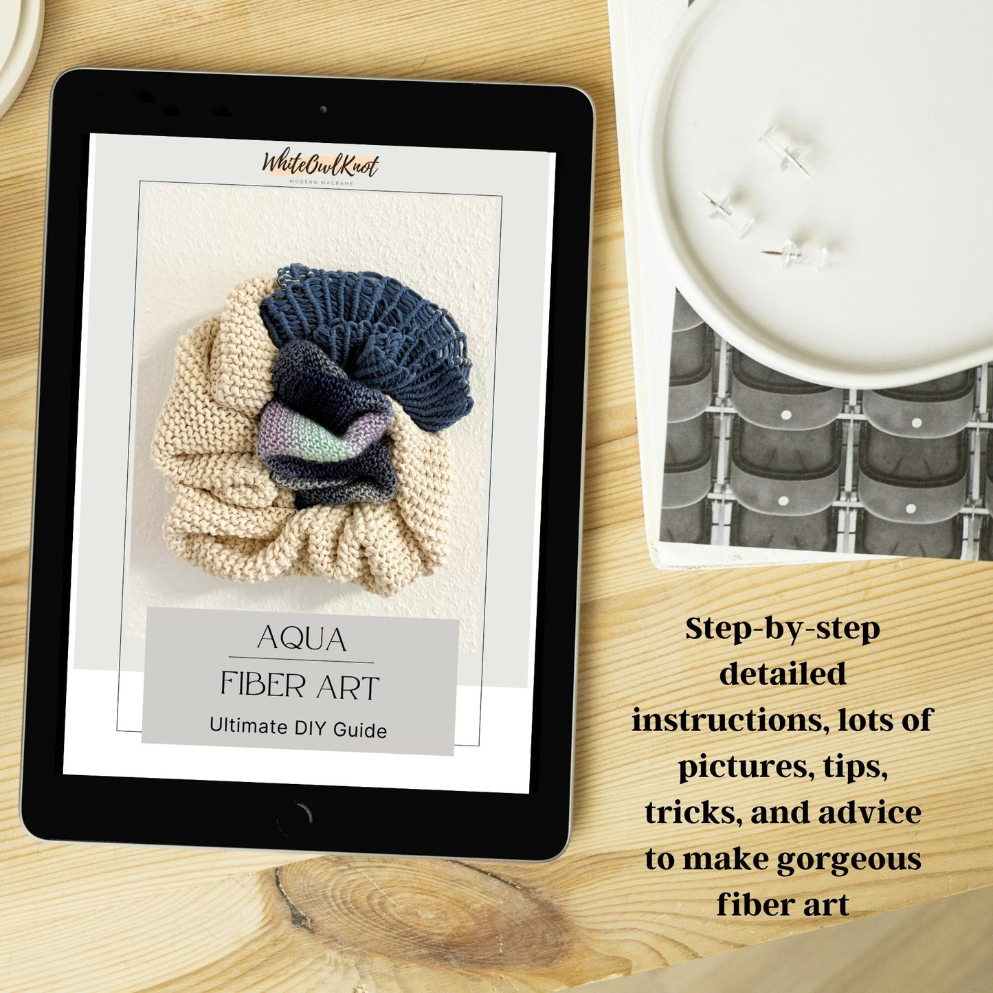 Tablet displaying a fiber art guide on a wooden surface with yarn and knitting tools.