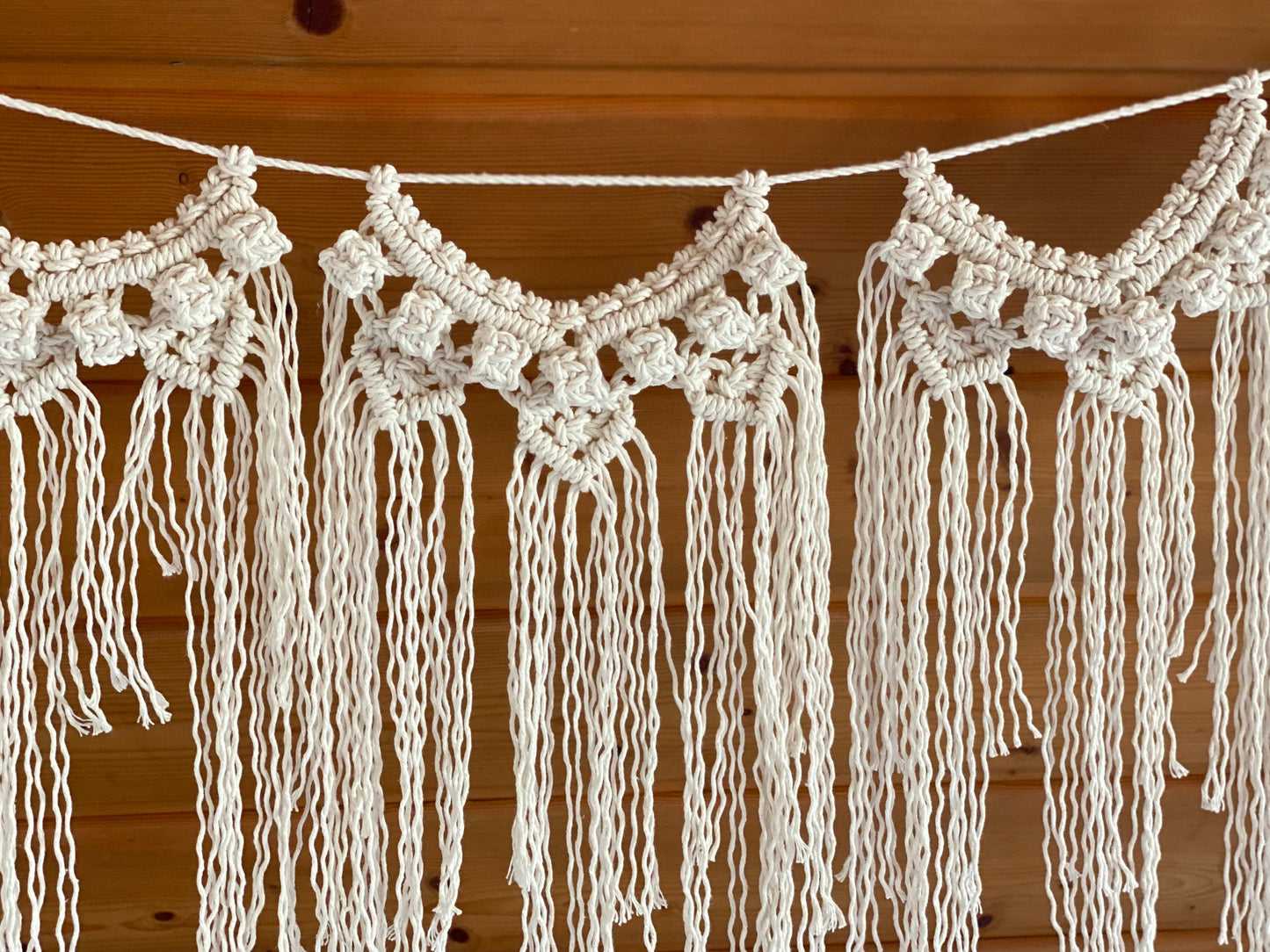 Macrame wall hanging with tassels on a wooden background