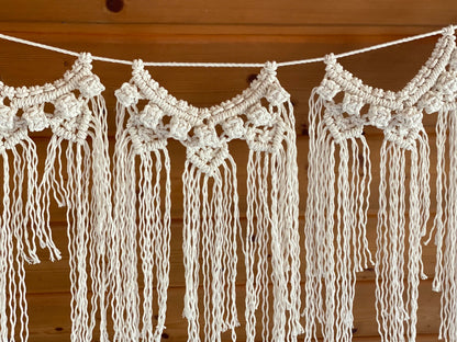 Macrame wall hanging with tassels on a wooden background