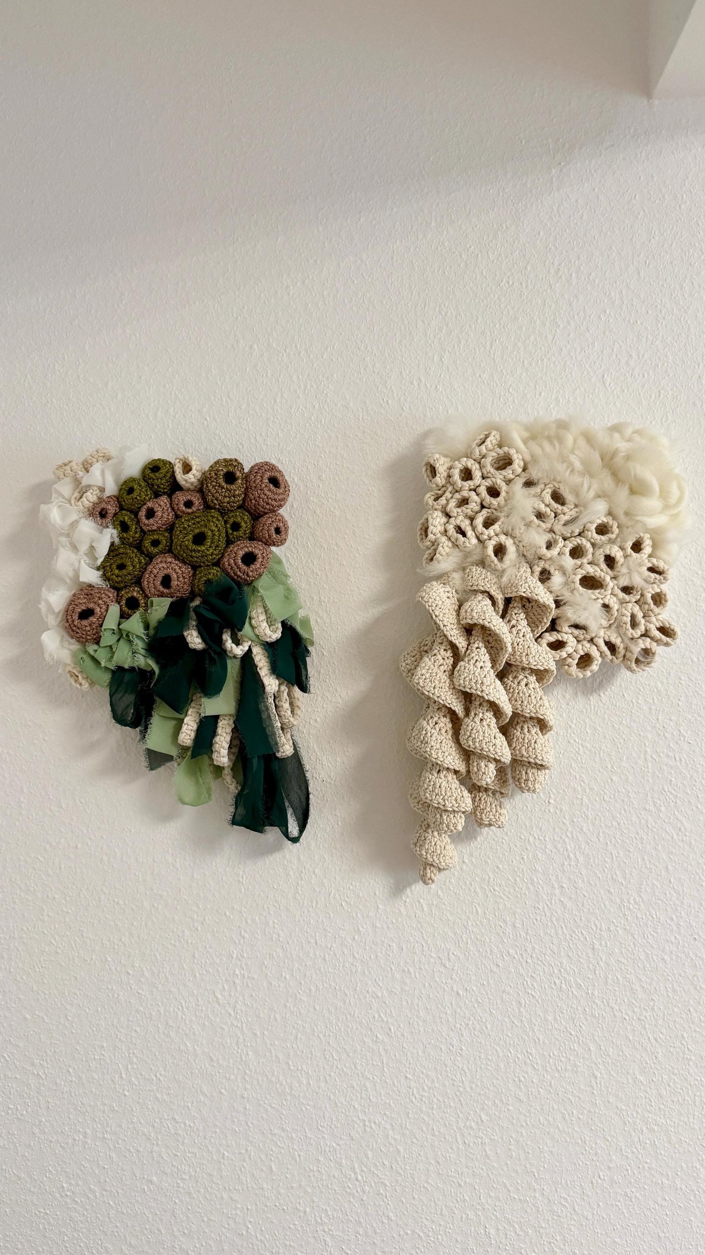 Two wall-mounted decorative pieces, one floral and one woven, on a plain white background.