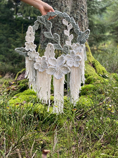 Decorative wreath with floral patterns held by a hand in a natural setting.
