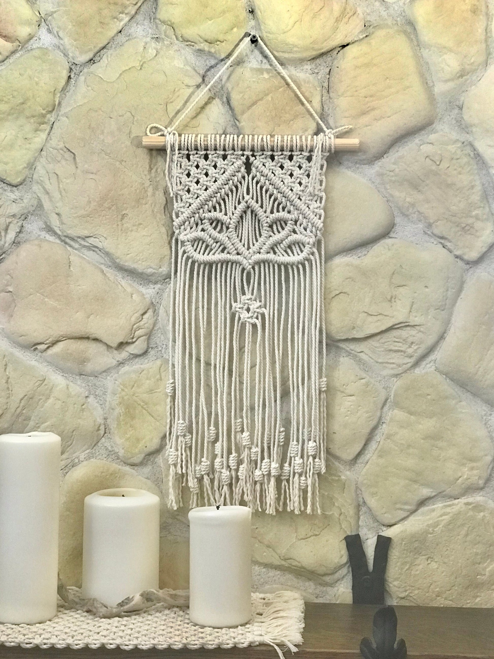 Macrame wall hanging on a stone wall with candles below