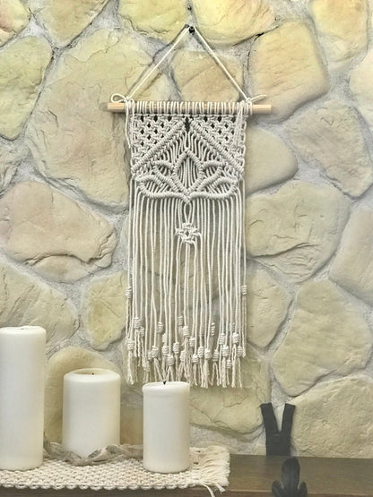 Macrame wall hanging on a stone wall with candles below
