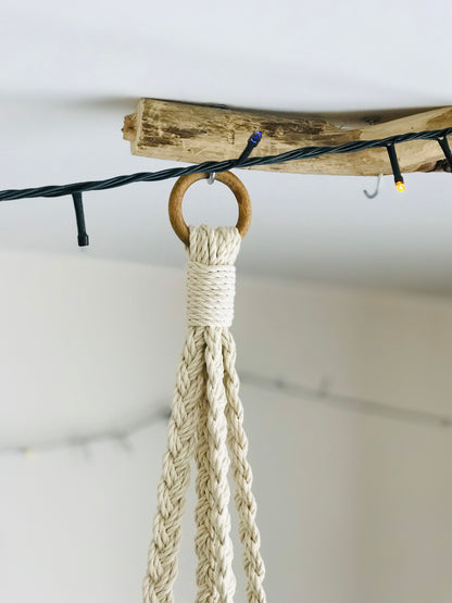 Macrame plant hanger with wooden ring and natural rope on a white background