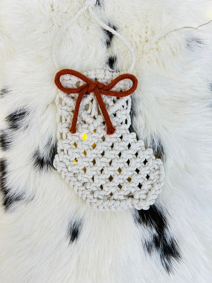 White macrame christmas ornament with a brown bow on a fur background