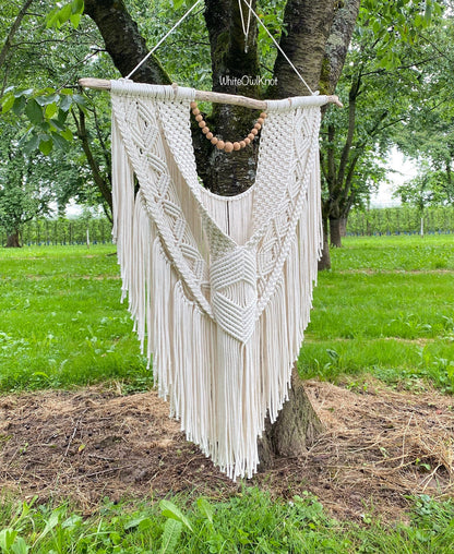 Macrame wall hanging hanging from a tree in an outdoor setting