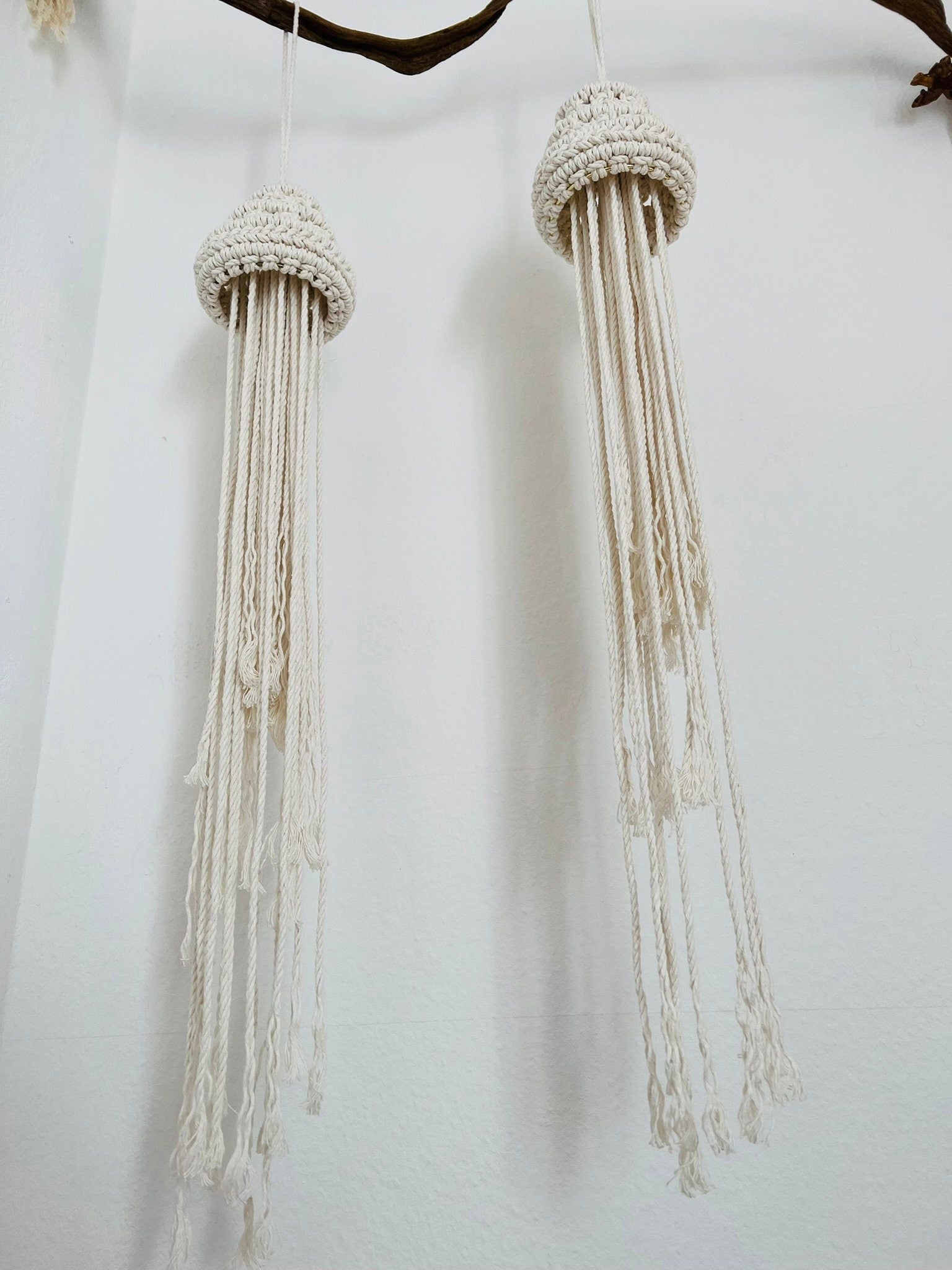 Two macrame jellyfish with bead tops on a white background