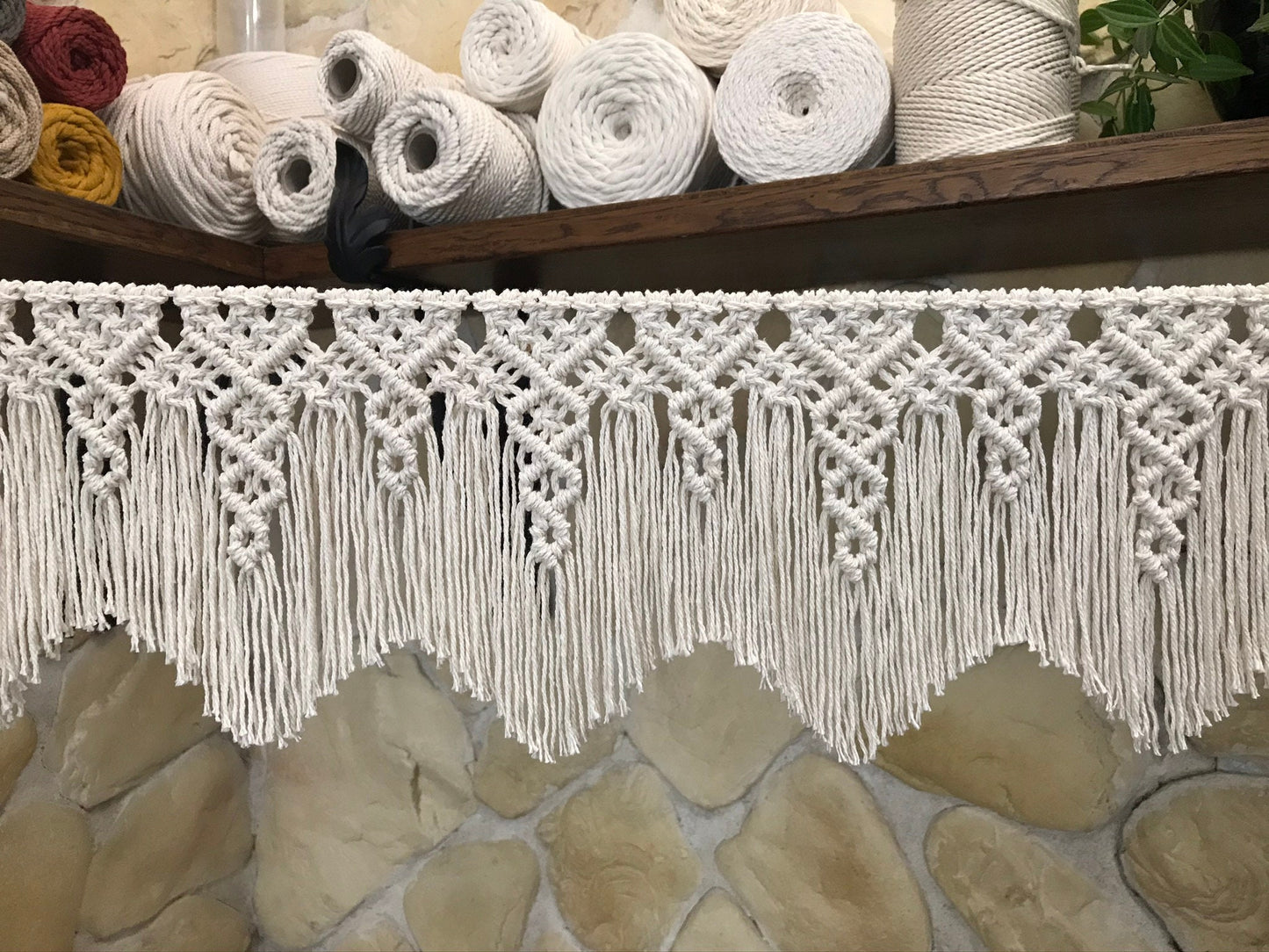 Macrame garland with fringes with yarn rolls in the background