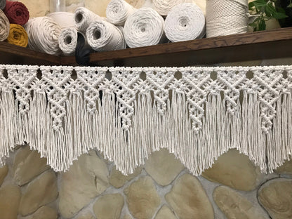 Macrame garland with fringes with yarn rolls in the background