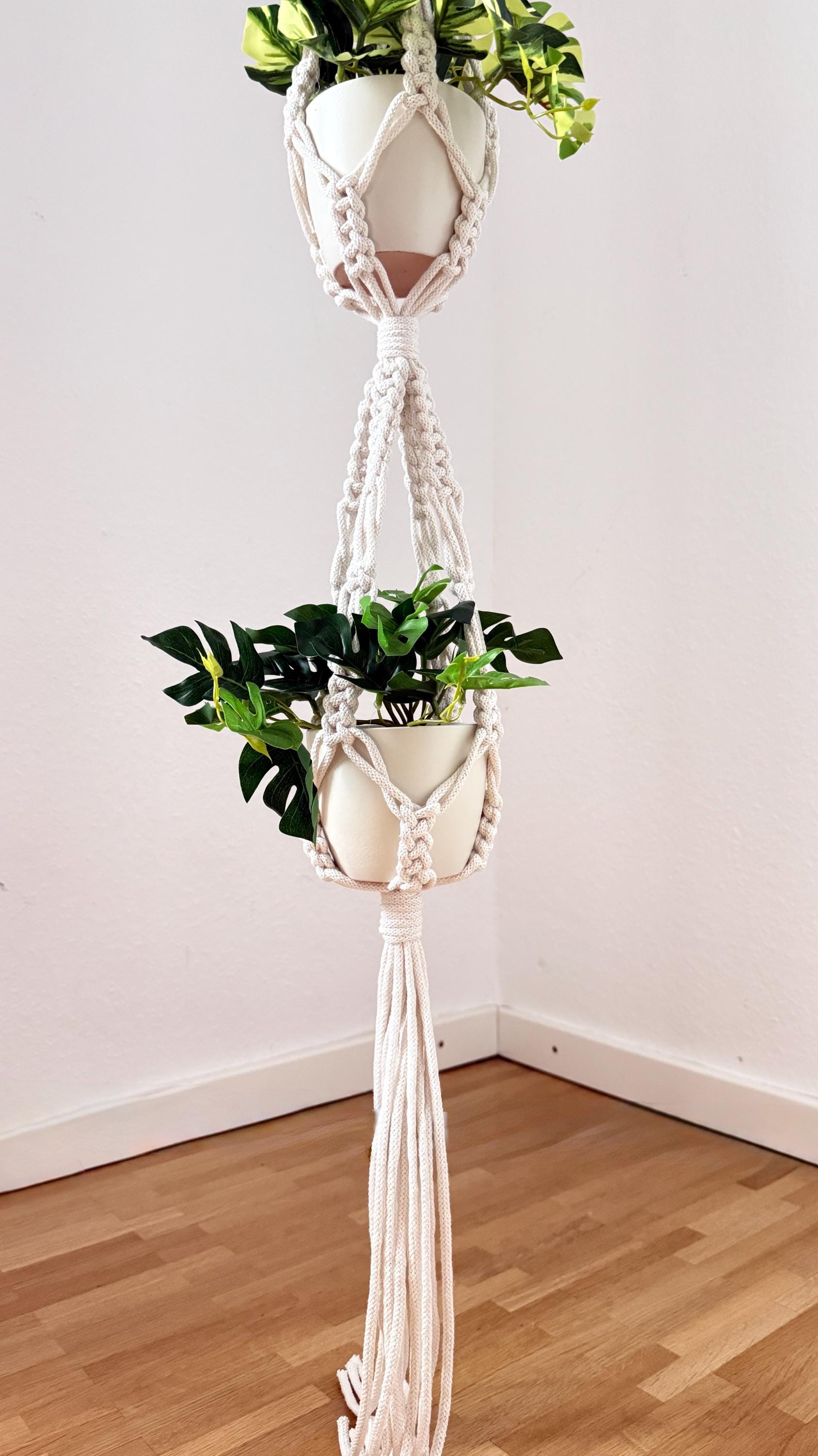 Macrame plant hanger with a plant on a wooden floor against a white wall