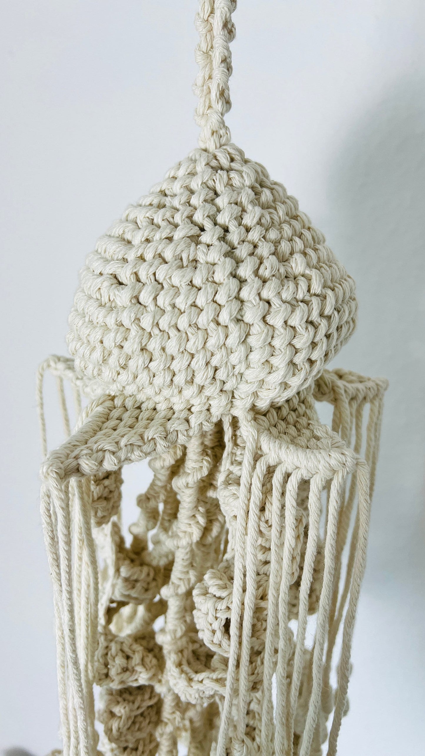 Beige macrame jellyfish against a white background