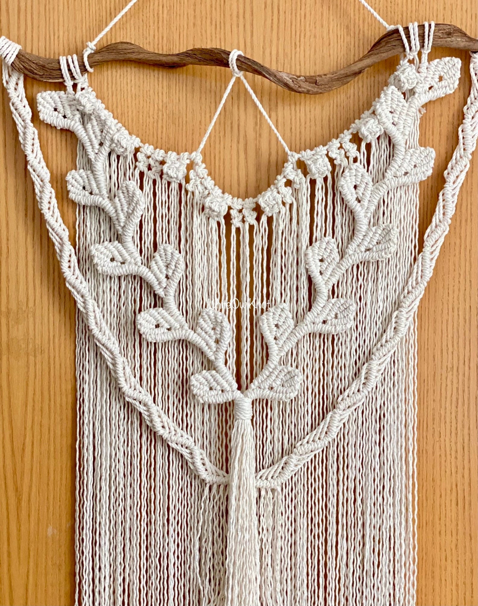 Macrame wall hanging with leaf patterns on a wooden background