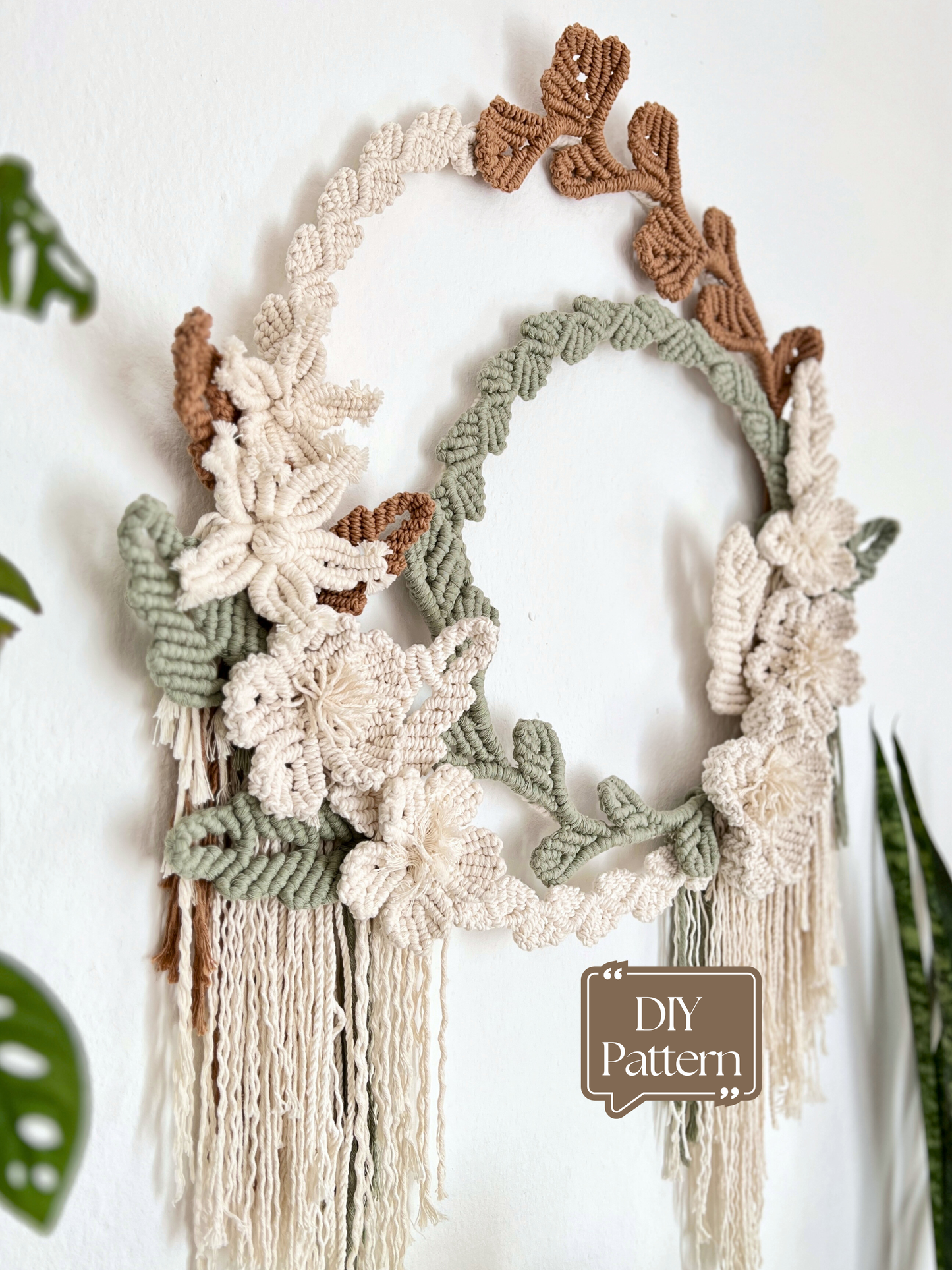 Macrame wall hanging with floral and leaf patterns on a white background