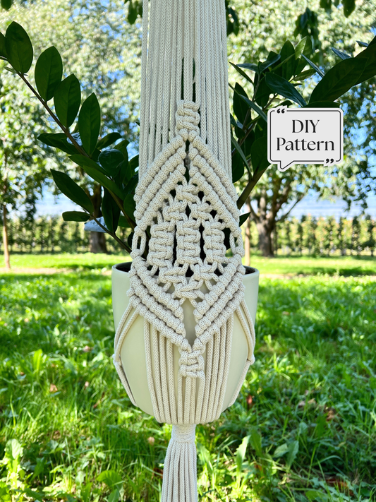 Macramé plant hanger pattern featuring a detailed geometric knot design, photographed outdoors with a potted plant hanging among green foliage.