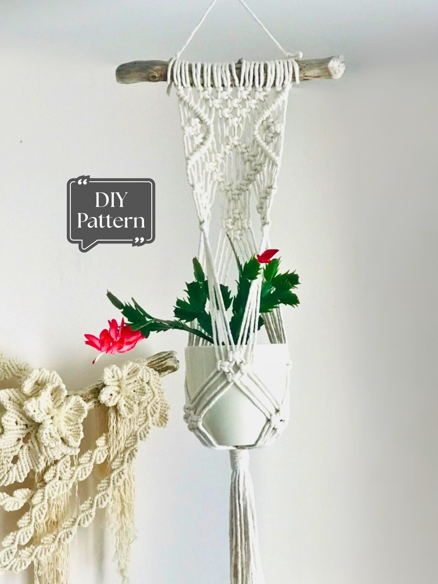 White macramé wall-mounted plant hanger with a decorative knotted design, hanging from a wooden branch and holding a potted plant indoors; DIY macramé PDF pattern