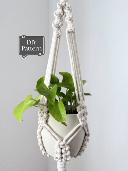 Macrame plant hanger with a potted green plant, featuring textured knotted details and a clean, minimalist design, shown as a DIY PDF pattern example on a light background.