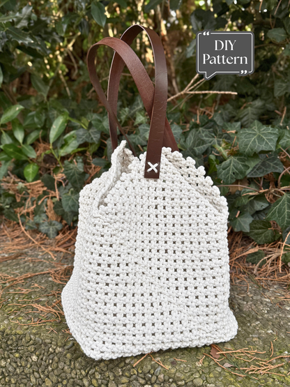 DIY macramé bag pattern with leather handles, featuring a textured knotted design and a soft drawstring-style top, photographed outdoors against green foliage.